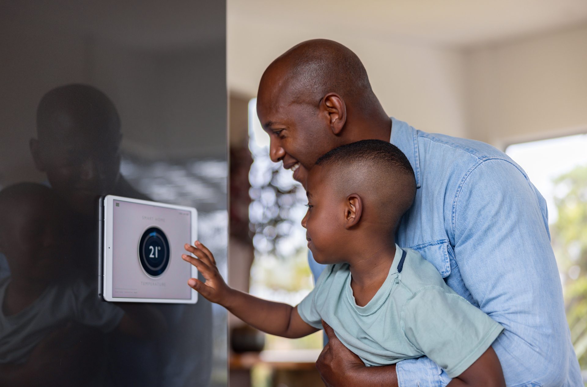 Father and son adjusting a smart thermostat
