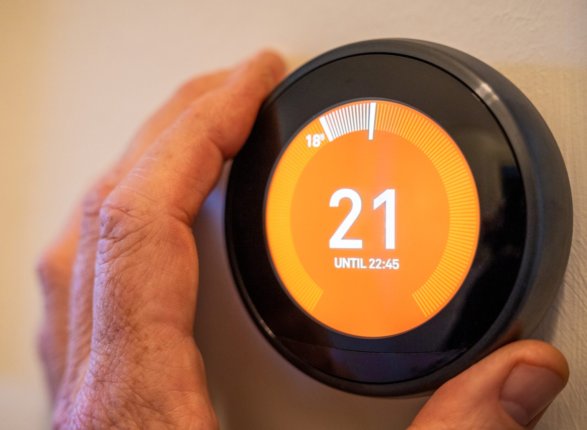 Hand adjusting a smart thermostat on the wall